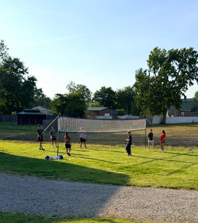 Group playing volleyball outdoors in sunlight.