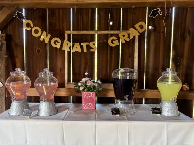 Graduation drink station with festive decorations and flower centerpiece.