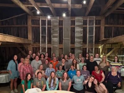 Large group posing in a rustic wooden barn.
