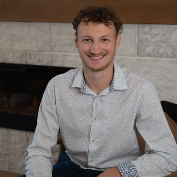 Young man smiling while sitting in a chair indoors.