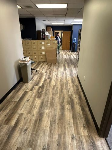 Office hallway with filing cabinets and a man standing near a doorway.