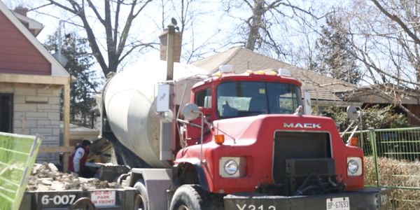 Red Mack cement mixer truck parked at a construction site.