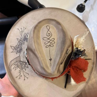 A beige hat with intricate designs and floral decorations.