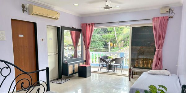 Bright room with two beds, balcony, and pink curtains.