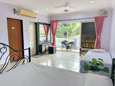 Bright room with two beds, balcony, and pink curtains.