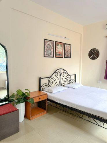 Minimalist bedroom with black iron bed, wooden nightstand, and decorative wall art.