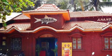 Anand Bar seafood restaurant with parked motorcycles outside under palm trees.