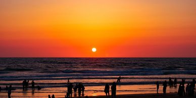 Silhouettes of people enjoying a vibrant sunset on the beach.