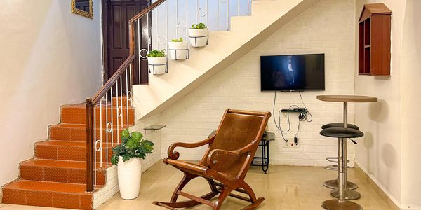 Cozy living area with a wooden rocking chair and TV under the staircase.