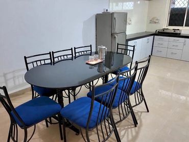 Modern kitchen with a black dining table and blue cushioned chairs.