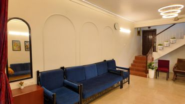 Cozy living room with blue sofa, modern lighting, and staircase adorned with plants.