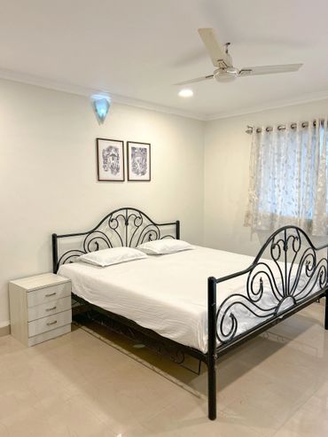Minimalist bedroom with black metal bed, white bedding, and a small nightstand.