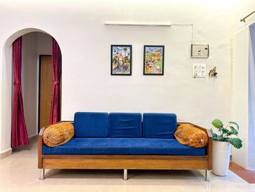 A modern wooden sofa with blue cushions and orange pillows in a cozy living room.