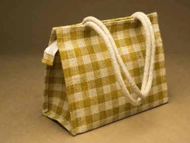 Checkered fabric bag with thick rope handles on a brown background.