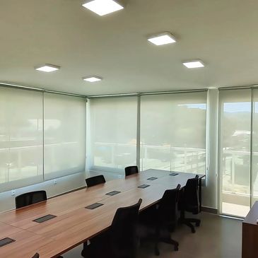 Sala de reunião com mesa longa e cadeiras pretas.
