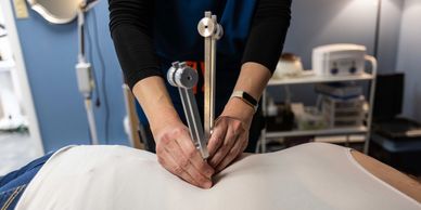 practitioner holding tuning forks against a patient's back