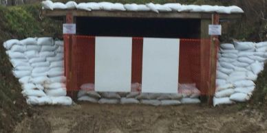 Outdoor shooting range target with sandbags and backstop.