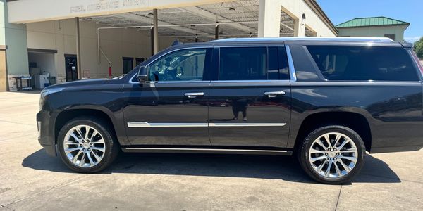 Black luxury SUV parked outside under clear sky.