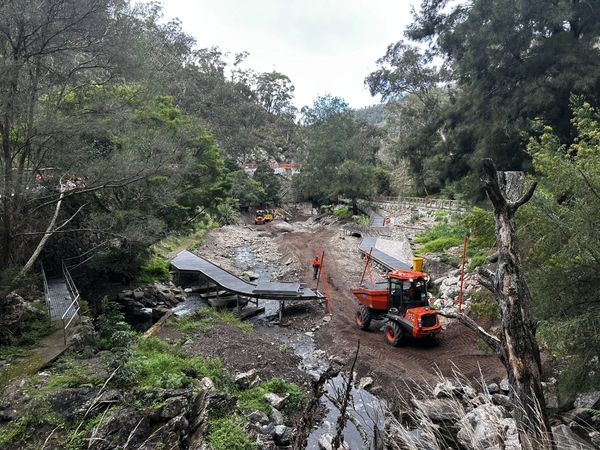 Construction work on a riverbank in a forested area with machinery.