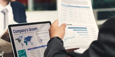 Businessman reviewing company growth charts on laptop and paper.