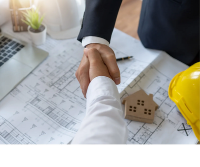 Two professionals shaking hands over architectural blueprints and a yellow hard hat.