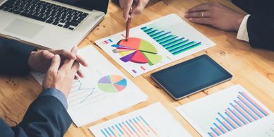 Business professionals analyzing colorful charts and graphs on a wooden table.