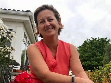A headshot of Carol Brill in a garden.