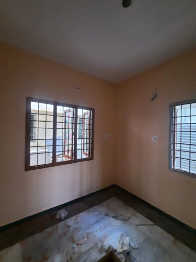 Empty room with two barred windows and a marble floor.
