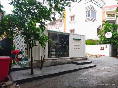 A small container cafe with trees outside on a quiet street.