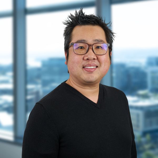 Man wearing glasses and black sweater smiling indoors.