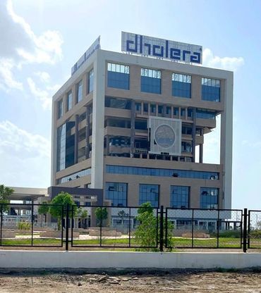 Modern multi-story office building with glass windows and a large sign on top.