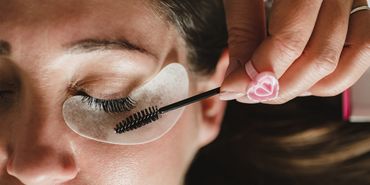 Applying mascara to eyelashes with eye pads.