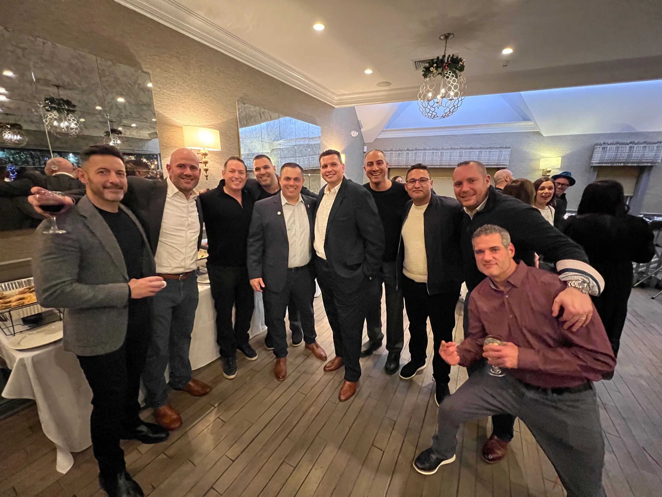 A group of men enjoying a social gathering indoors, smiling and holding drinks.