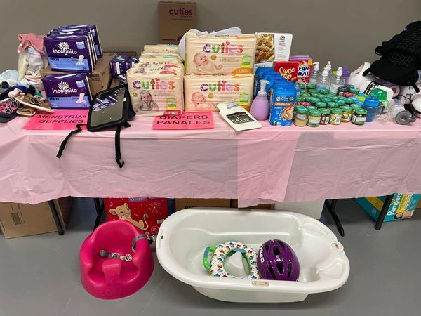 Table with baby supplies including diapers, bath tub, and food jars.