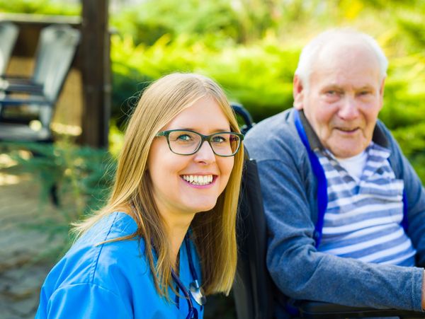 Carer nursing elderly man in a home garden