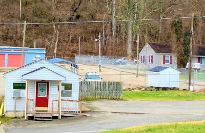 Small houses and storage units in a rural area with a hillside backdrop.
