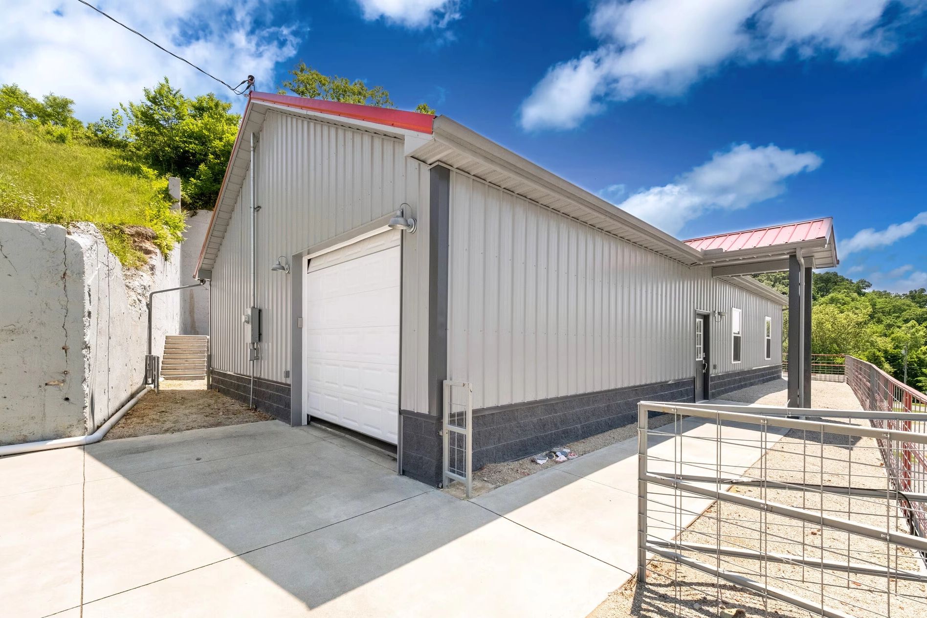 Modern metal garage with red roof under a blue sky.