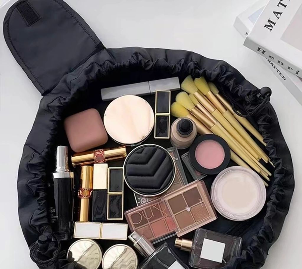 Open black makeup bag filled with brushes, lipsticks, powders, and palettes.