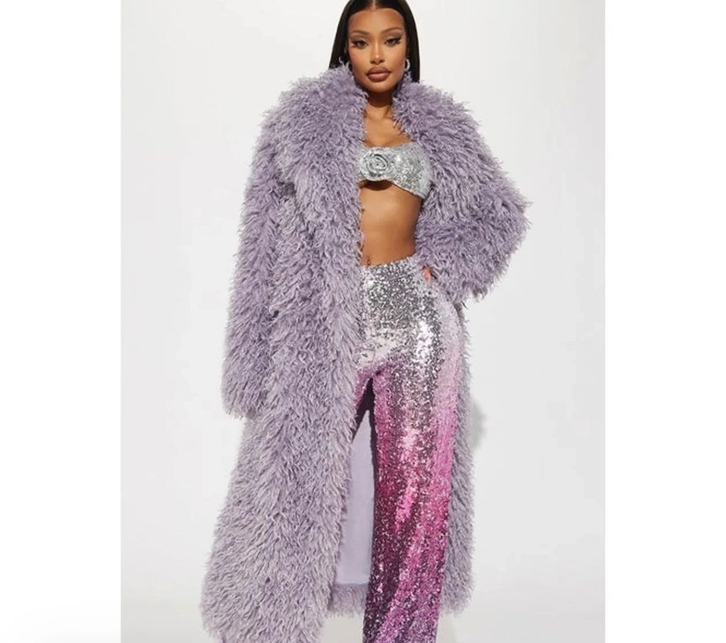 Fashion model in a lavender fur coat and sparkling sequin pants.