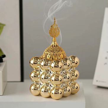 Golden decorative incense burner emitting smoke indoors.