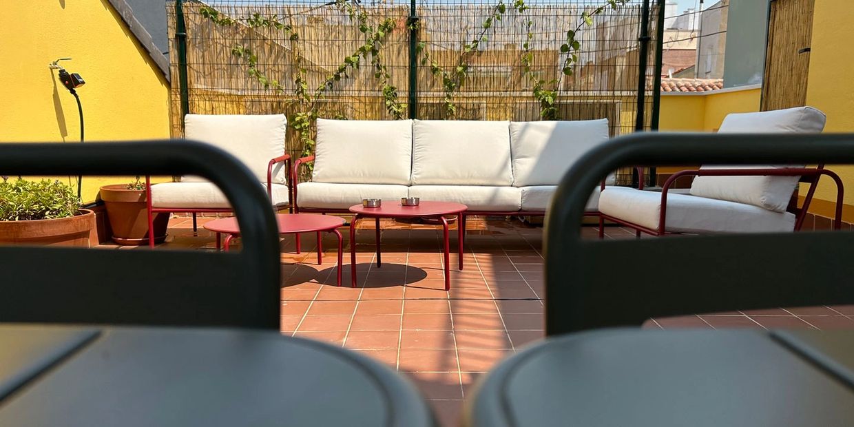 mesas verdes metalicas y de fondo una sofá exterior blanco