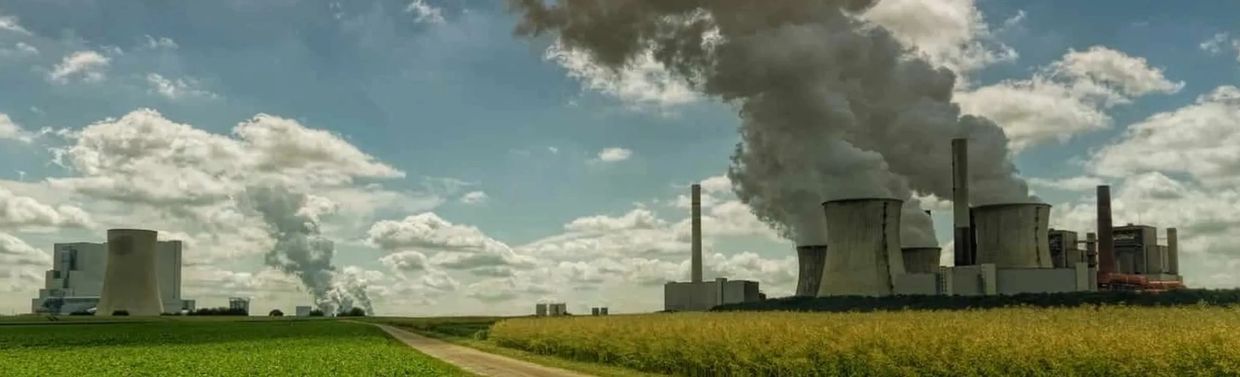 Power plants emitting smoke under a cloudy sky.
