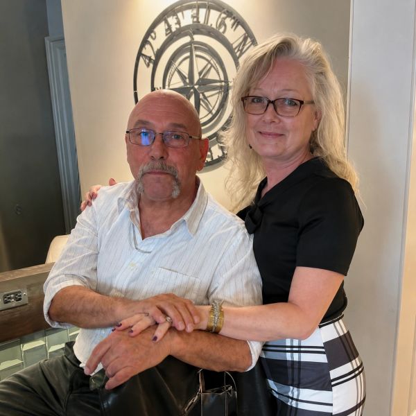 Couple posing together indoors, smiling gently.