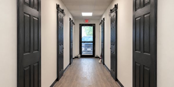 Hallway with black sliding barn doors and a glass exit door at the end.