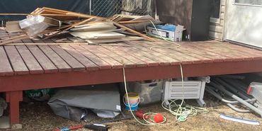 Messy backyard deck with scattered tools and wooden planks.