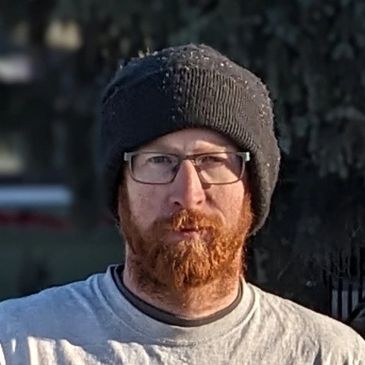 Owner standing outdoors in front of a residential home during an asphalt replacement. Edmonton