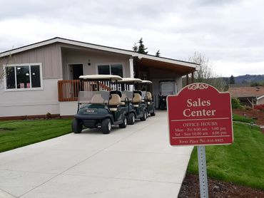 Golf carts lined up outside a sales center with office hours sign.