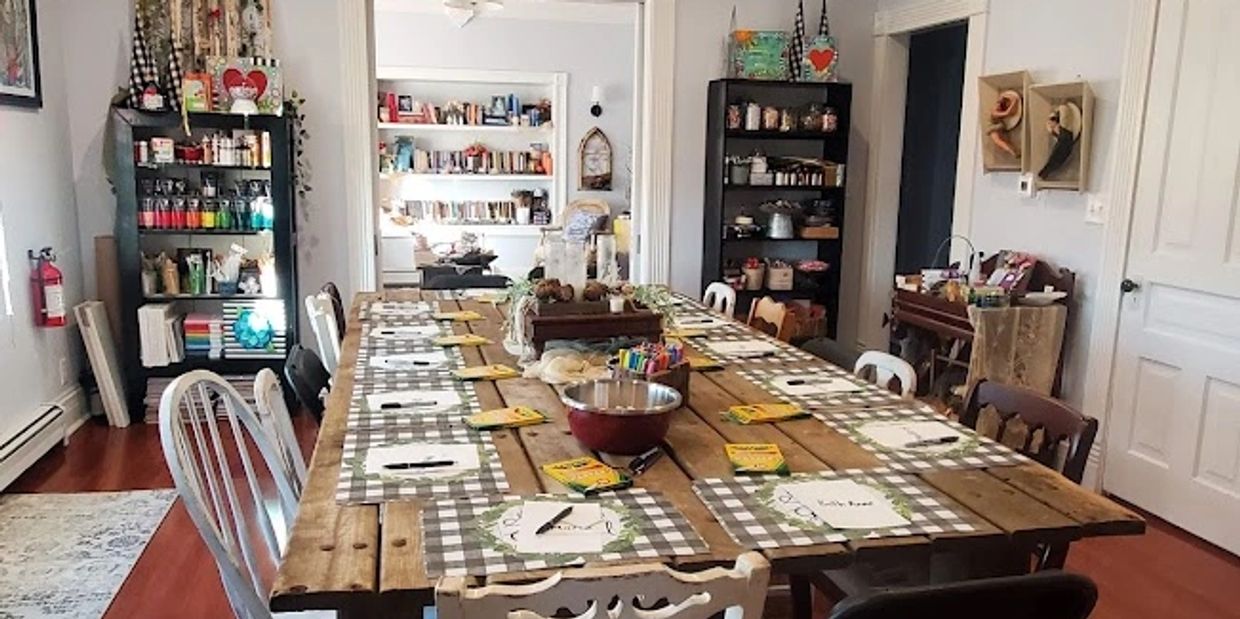 A cozy craft room with a large wooden table and art supplies.
