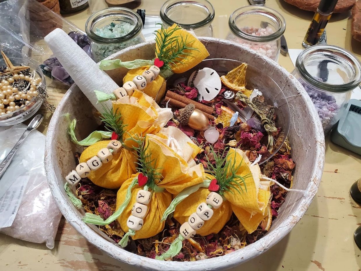 Decorative yellow sachets labeled with words, surrounded by dried flowers and jars of crystals.