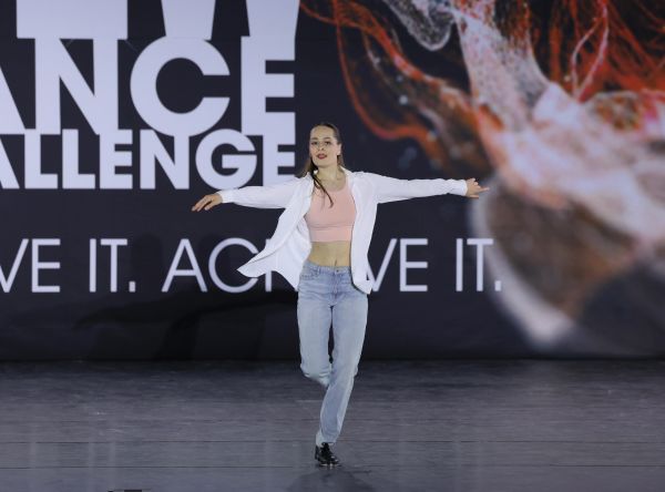 Woman dancing on stage with arms extended.